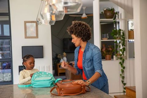 Mother and daughter unpacking backpack in modern home