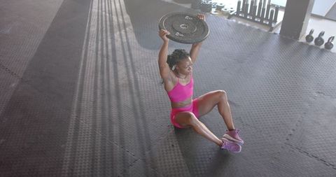 Woman's athletic exercise with weight plate in gym