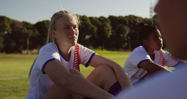 Serious Female Football Player Sitting in Field with Teammates - Download Free Stock Images Pikwizard.com