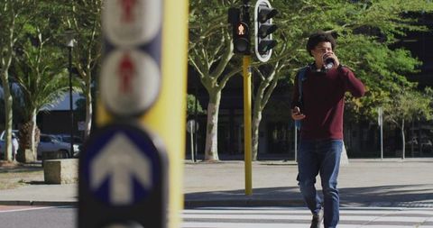 Young Man Walking Across Street With Phone and Coffee in City