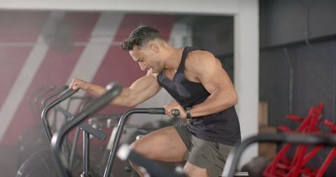 Focused Man Exercising on Stationary Bike in Gym