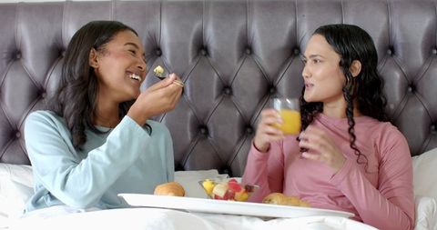 Diverse women enjoying cozy breakfast in bed together