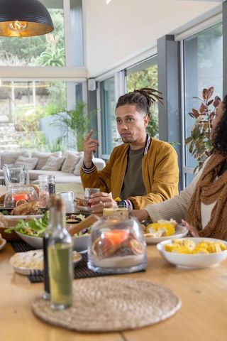 African American couple sharing brunch in modern open-plan dining, man holding glass
