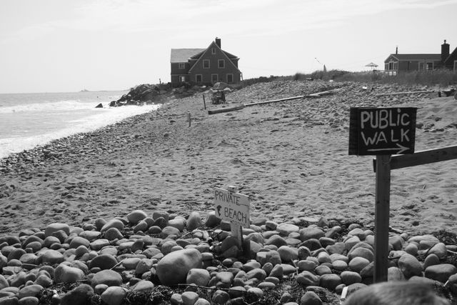 Peaceful coastal scene showcasing a secluded beach with signage for private beach and public walk differentiating areas. Utilized for topics like seclusion, privacy, coastal living, or real estate.
