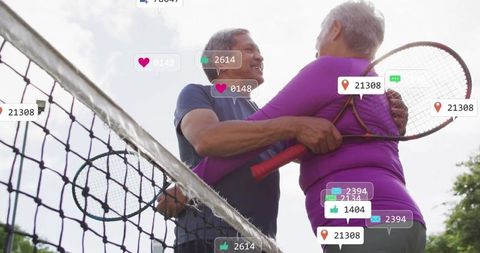 Senior couple embracing while playing tennis together outdoors