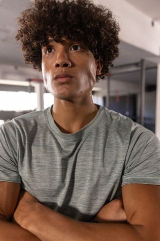 African american athlete standing with arms crossed showing muscular build in gym