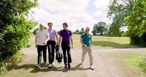 Group of Male Friends Walking on Golf Course with Golf Gear