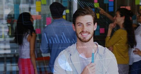Smiling young professional holding teal marker during collaborative office brainstorming