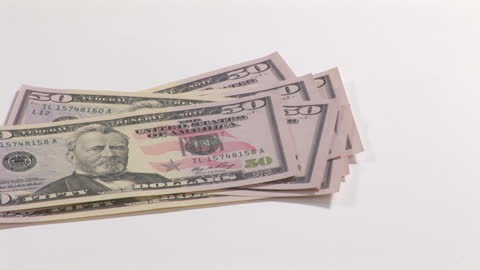 Stack of U.S. Fifty Dollar Bills on White Surface