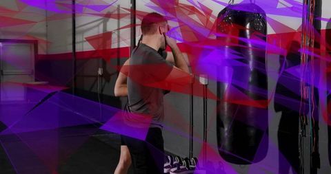 Man training with heavy punching bag and partner in gym with purple light streaks