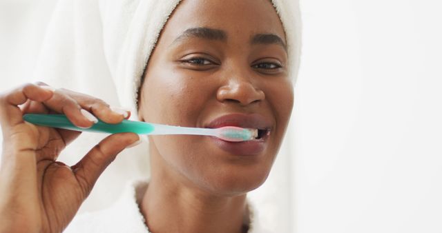 Woman with towel on head brushing teeth and smiling - Download Free Stock Images Pikwizard.com