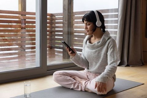 Woman Practicing Mindfulness Indoors with Smartphone and Headphones