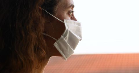 Woman in face mask practicing self-isolation at home