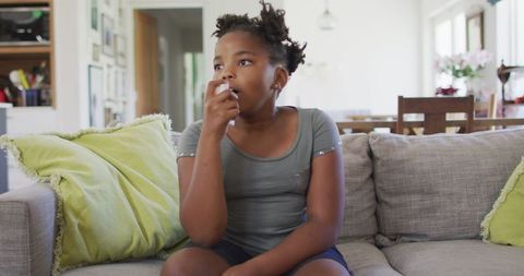 Young Girl Using Inhaler on Comfortable Sofa in Living Room Setting