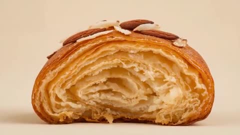 Camera zooming into almond croissant half revealing flaky layers and sliced almonds