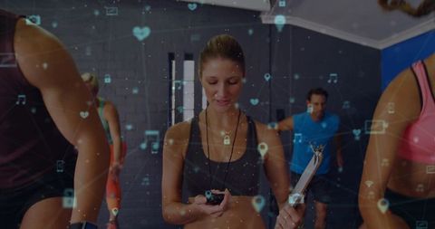 Female fitness coach timing cardio class with stopwatch, clipboard and wearable tech overlay