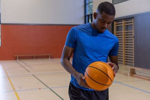 African american athlete holding basketball on indoor gym court preparing for practice
