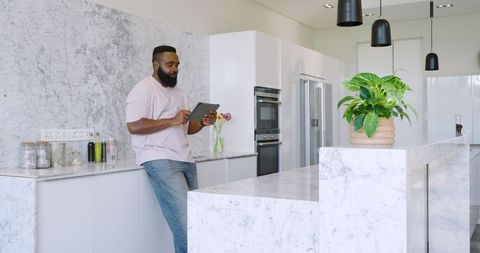 Man Relaxing in Modern Kitchen Marble Countertop with Tablet