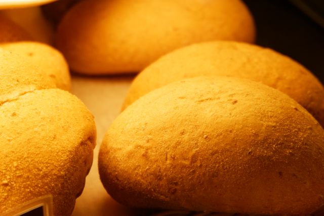 This close-up of freshly baked bread rolls showcases their golden brown, warm, and inviting appearance. Ideal for use on bakery websites, food blogs, and other culinary-related publications. Perfect for promoting fresh, homemade baked goods or organic produce.