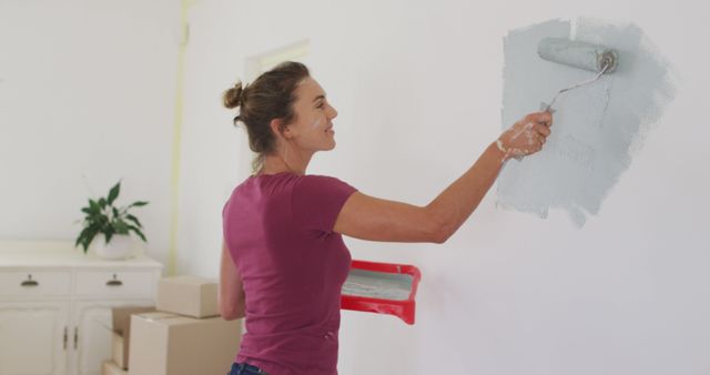 Happy caucasian woman painting walls with gray paint. Lifestyle, domestic life, house interior and work, unaltered.
