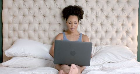 Biracial Woman Relaxing in Bedroom with Laptop - Download Free Stock Images Pikwizard.com