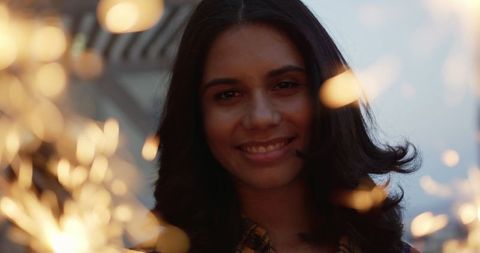 Joyful Young Biracial Woman Celebrates with Sparklers on Rooftop