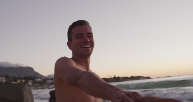 Smiling Man Holding Hands on Scenic Beach at Sunset - Download Free Stock Images Pikwizard.com