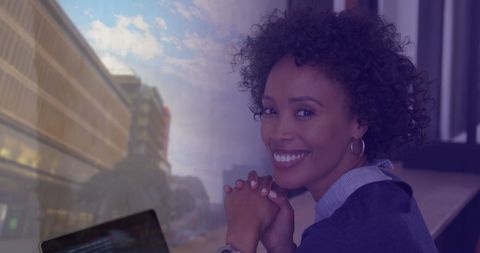 Biracial Businesswoman Smiling with Laptop Over Urban Cityscape