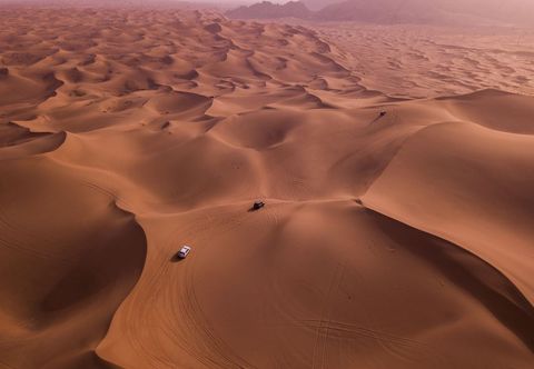 Aerial View of Vehicles Adventuring in Serene Sand Dunes at Sunset