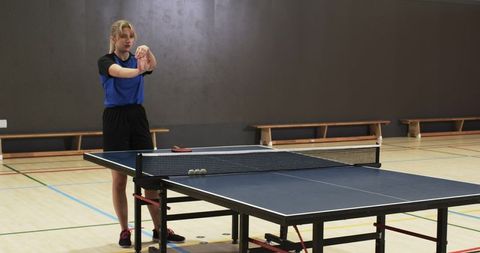 Female Athlete Stretching Before Table Tennis Match in Sports Hall