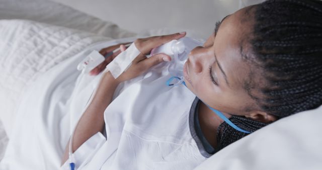 Young female patient lying in a hospital bed, receiving oxygen treatment and intravenous therapy. Ideal for articles on healthcare, medical treatment, hospital stay, patient experiences, and wellness.