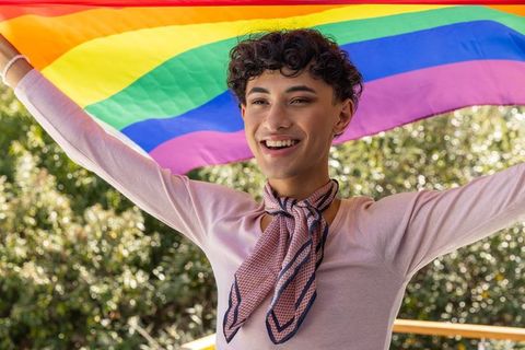 Smiling Man Holding Rainbow Flag Celebrating Diversity Outdoors