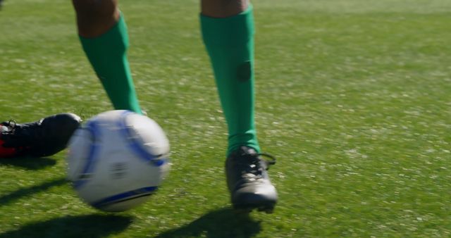 Close-up of a soccer player's feet on the field, with copy space. Action shot captures the dynamic movement of the game outdoors.