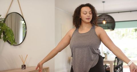 African american woman stretching and meditating in bright minimalist home living space