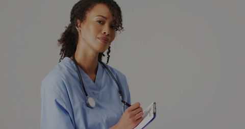 Smiling Nurse Writing in Clinic with Clipboard and Stethoscope