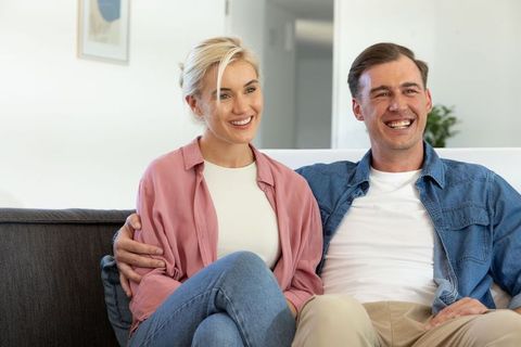 Happy couple relaxing together on sofa laughing in modern minimal living room
