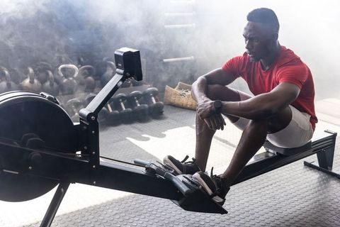 African american man resting on rowing machine after intense workout in industrial gym