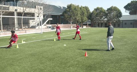 Teen Soccer Players Practicing Footwork Drills with Coach on Field