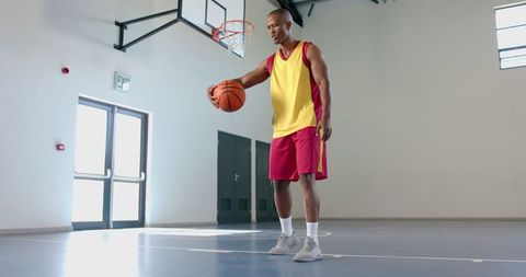 Focused African American Male Practicing Basketball in Indoor Gym