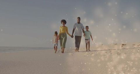 African american family walking hand in hand on sunlit beach leaving footprints with bokeh