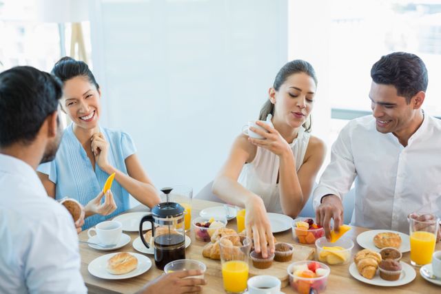 Group of business colleagues enjoying breakfast together in an office cafeteria. They are interacting, smiling, and sharing food, creating a friendly and collaborative atmosphere. Ideal for illustrating workplace culture, team bonding, corporate meetings, and professional environments.