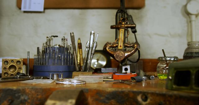 An old-fashioned workshop table is filled with various tools, including drills, pliers, and intricate machinery, creating a nostalgic atmosphere. This image is ideal for illustrating themes related to craftsmanship, DIY projects, engineering, vintage aesthetics, and passionate hobbies.