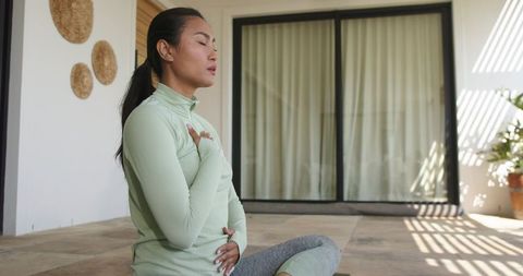 Sunlit terrace meditation by asian woman practicing breathwork and mindfulness for wellness