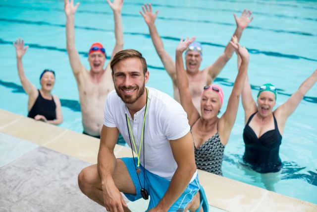 Portrait of male instructor with carefree senior swimmers in pool