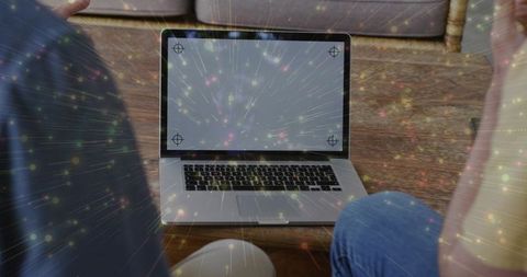 Two men leaning over laptop with digital light streaks in casual living room