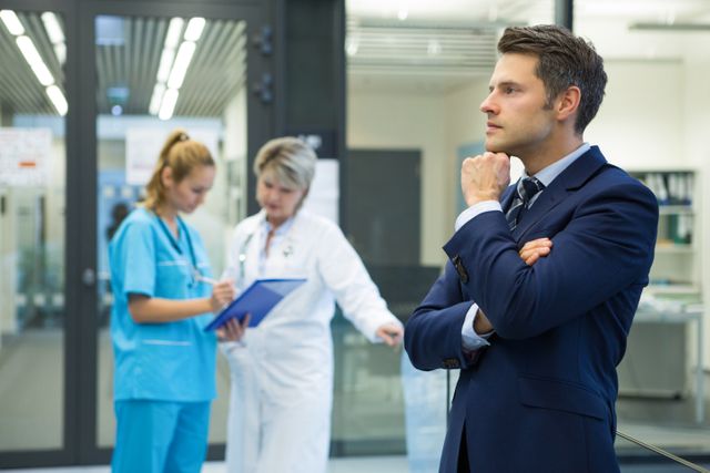 Thoughtful businessman standing in corridor at hospital