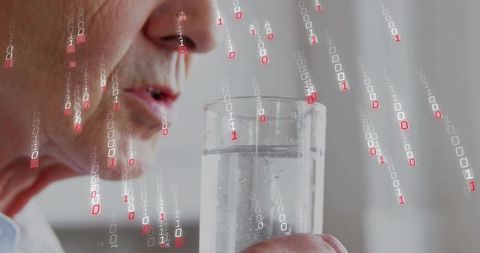Senior man drinking water with falling binary code overlay representing digital health data