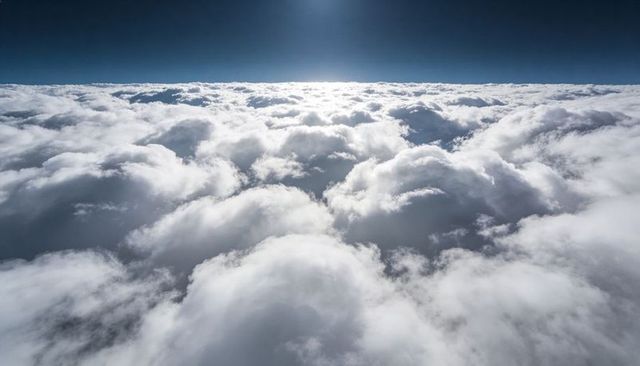 Glowing sunlit cumulus dome cloudscape from aerial perspective over bright horizon