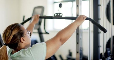 Woman Exercising on Lat Pulldown Machine for Rehabilitation in Gym