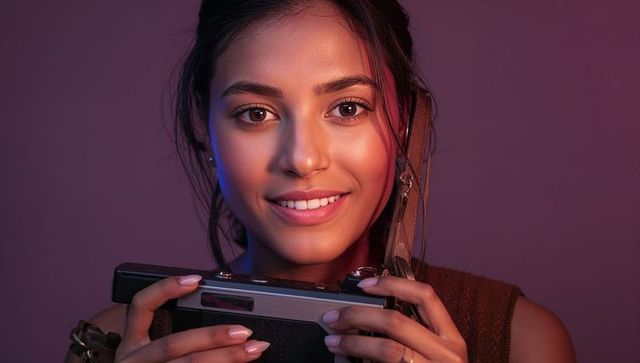 Young Woman Holding Vintage Rangefinder Camera with Leather Strap, Warm Studio Portrait